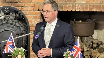 Ein Mann im Anzug und mit Brille steht an einem Rednerpult.