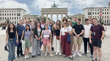 Eine Gruppe junger Menschen steht vor dem Brandenburger Tor.
