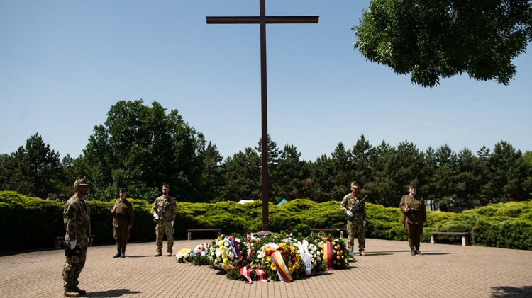 Auf der Kriegsgräberstätte: ein Hochkreuz mit Kränzen und Soldaten