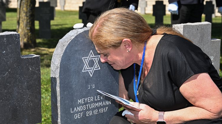 Frau kniet an einer Grabstele.